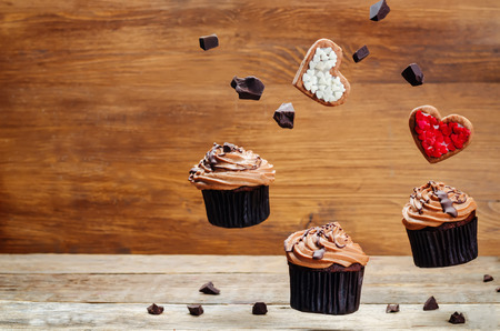 Flying chocolate cupcakes and cookies in the forms of heart. toning. selective focusの写真素材