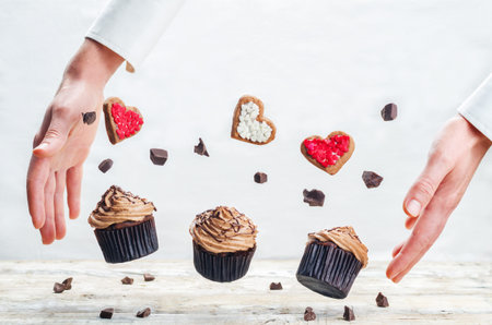 Male hand with flying cookies and cupcakes. toning. selective focusの写真素材