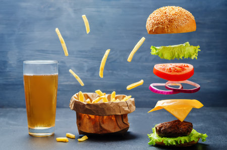 Flying burger with flying French fries and beer on a dark background. toning. selective focusの写真素材