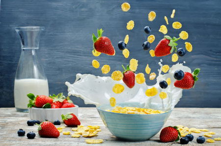 Healthy breakfast with milk, flying corn flakes, strawberries and blueberries. toning. selective...