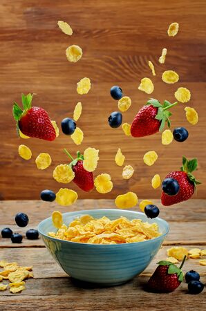 Healthy breakfast with flying corn flakes, strawberries and blueberries. toning. selective focusの写真素材