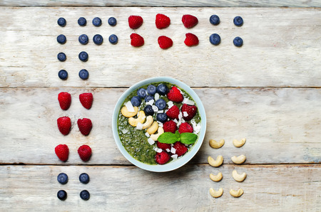 Spinach smoothies breakfast bowl with coconut flakes, raspberry, blueberry and cashews. toning. selective focusの写真素材
