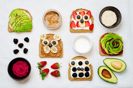 Variation of healthy rye breakfast sandwiches with avocado, hummus, and berries. toning. selective focusの写真素材