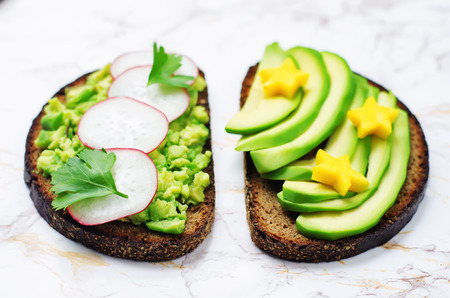 Avocado mango and smashed avocado radish parsley rye breakfast sandwiches. toning. selective focusの写真素材