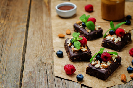 Raw vegan no bake chocolate dates almond brownies with chocolate frosting and berries. toning. selective focusの写真素材