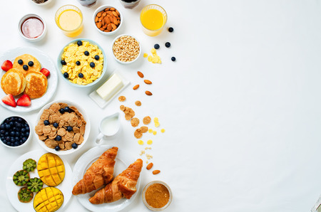 Breakfast table setting with flakes, juice, croissants, pancakes and fresh berries. toning. selective focusの写真素材