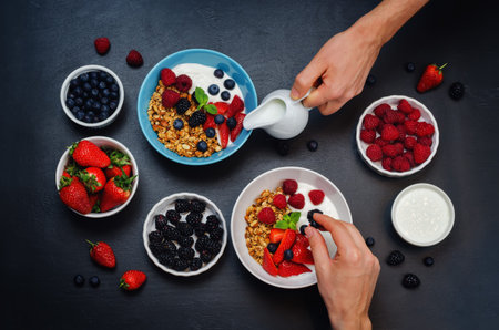 Male hands with healthy breakfast with granola, greek yogurt, berries and milk. toning. selective focusの写真素材