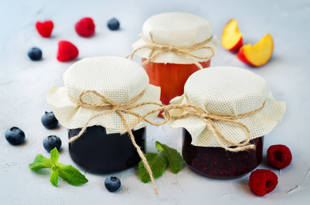set of jams: raspberry, blueberry and peach. toning. selective Focusの写真素材