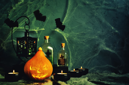Halloween horror background with a spider's web, pumpkin; candles, potions and bats. Space for your holiday text on Halloweenの写真素材