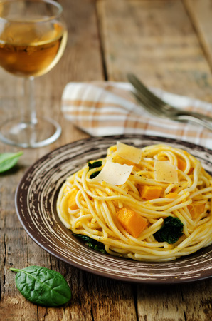 Pasta with pumpkin and spinach on a wood background. toning. selective focusの写真素材