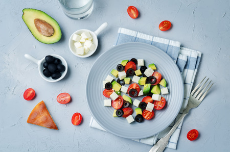 Avocado tomato black olives feta cheese salad on a stone background. toning. selective focusの写真素材