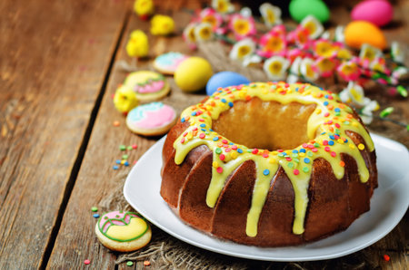 Easter Bundt cake with colorful topping and Easter Cookies on a wood background. tinting. selective focusの写真素材