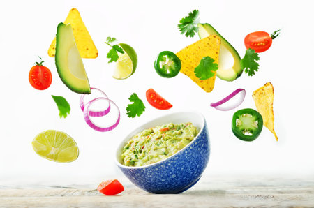 Guacamole with flying corn chips and ingredients to prepare it on a white background. toning. selective focusの写真素材