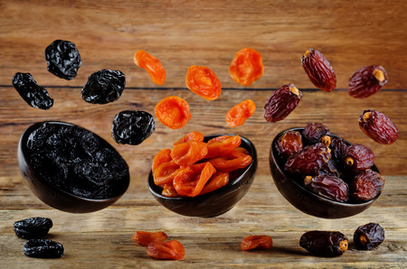 Variation of dried fruits: prunes, dried apricots, dates on a dark wood background. toning. selective focusの写真素材