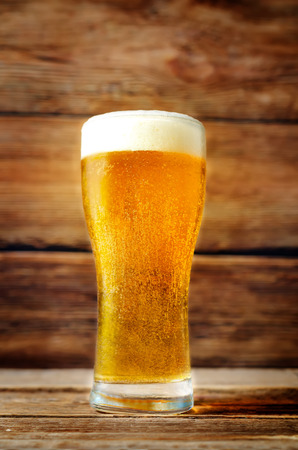 Glass of cold light beer on a wood  background. toning. selective focusの写真素材