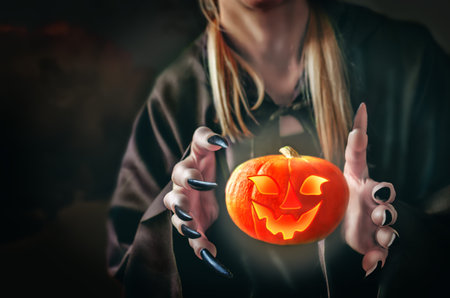 Witch's hands with a flying glowing pumpkin on a dark background for Halloween. Toning. selective...
