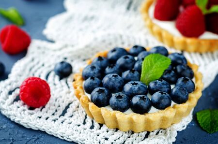 Raspberry and blueberry tartlets with fresh berries and mint leaves. Selective focusの写真素材