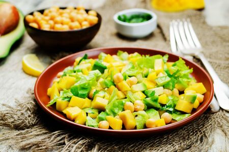 Mango avocado chickpeas salad on a wood background. Selective focusの写真素材
