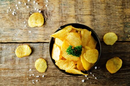 Potato chips with salt on a wood background. toning. selective focusの写真素材