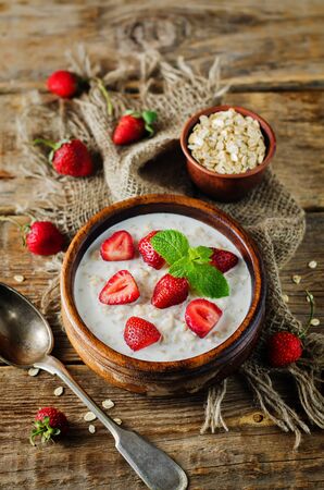 Oatmeal porridge with fresh strawberries and raspberries. toning. selective focusの写真素材