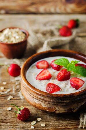 Oatmeal porridge with fresh strawberries and raspberries. toning. selective focusの写真素材
