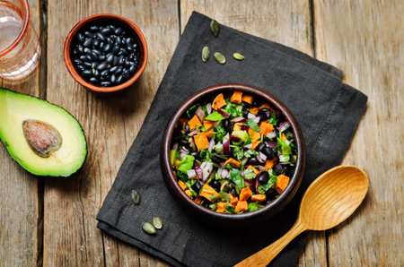 Black bean roasted sweet potato pepita avocado salad on a wood background. toning. selective focus