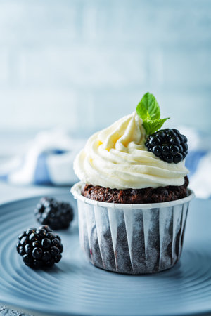 Chocolate banana cupcakes with cream cheese frosting and blackberries. toning. selective focusの写真素材