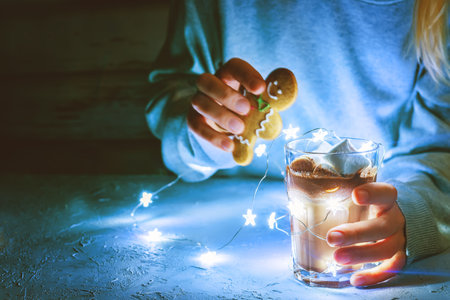 Woman with hot cocoa or chocolate and garland lights. toning. selective focus