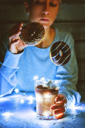 Woman with hot cocoa or chocolate and garland lights. toning. selective focusの写真素材