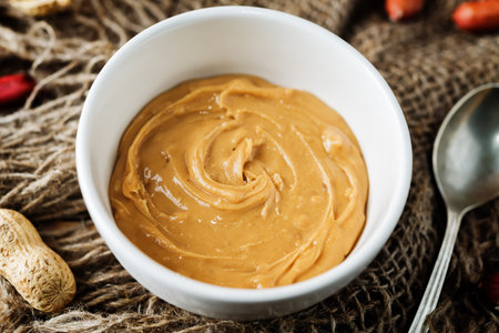 Peanut butter with peanuts on a dark wood background. toning. selective focus