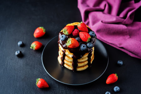 pancakes with chocolate glaze, strawberries, blueberries and raspberries. toning. selective focusの写真素材