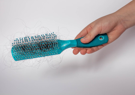 Hair loss problem, postpartum period, menstrual or endocrine disorder, hormonal disbalance, stress concept. Many hair fall after combing in hairbrush.Female untangles her hair with a comb, copy spaceの写真素材
