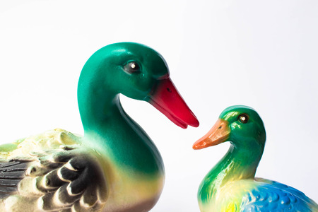 Ceramic statuette of a duck on a white background with brightly colored feathers.  Duckling with mother duck.の写真素材