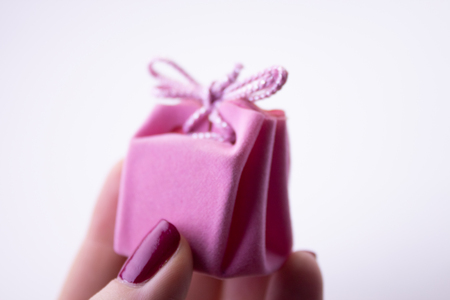 Pink gift box with ribbon for decorations in hand. Festive gift to a girl or woman.の写真素材