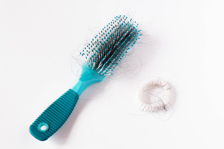 Girl Hairs fall with a comb and problem hair on white background. Hair fall or loss with blush is a problem of womenの写真素材