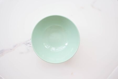 plate on white marble. green ceramic bowl on a white marble background. top view.の写真素材
