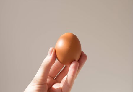 Easter layout on a white background. An egg with painted eyes in the hand of a young woman. Card with copy space.の写真素材