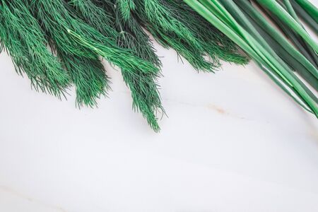 Flat layout of greens on a white marble table with copy space for text. Green onion feathers, dill, parsley, spinach.の写真素材