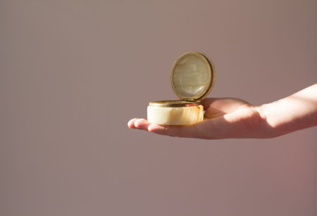 Onyx casket in a woman hand in the shadow of a tropical palm tree on a beige and gray background....