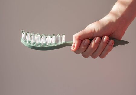 Comb in hand closeup mock up with text space. Haircare and beauty concept. Mockup, copy space.の写真素材