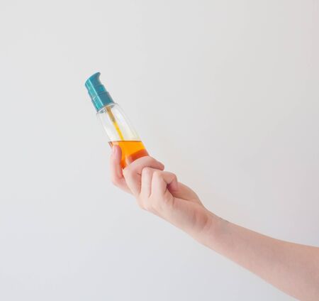 Girl holds cosmetic oil in blank vial blank with pump. Sea buckthorn oil for the treatment and rejuvenation of the skin.の写真素材