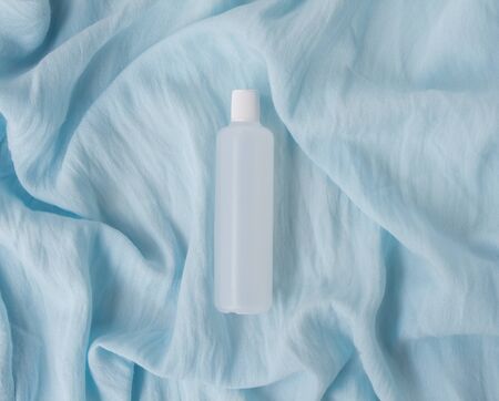 Creative layout on a blue background. White cosmetic jar with shadow. Stylish look of the product. Card with copy space.の写真素材