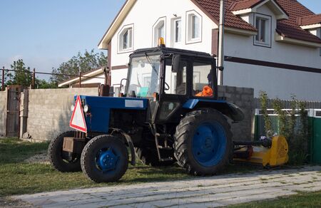  Tractor on the front lawn. Blue agricultural tractor for cultivating the land.の写真素材