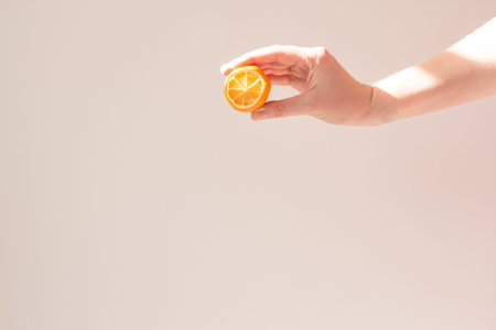 Lemon slice mock up in the hand of a young woman on a beige background with a beautiful shadow....