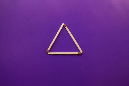  Isosceles triangle on a bright background. matchstick pyramid on cardboard. Education concept.の写真素材