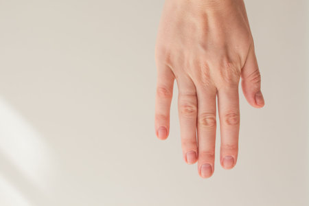  Female hand with natural manicure without gel polish on a white background with space for text....