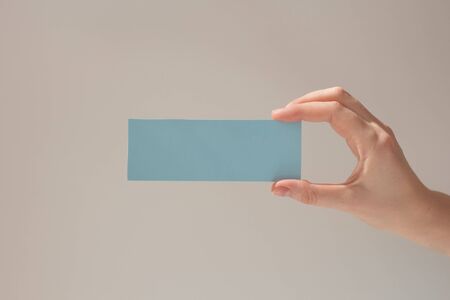 Hand hold blank business card. Mockup of female hands holding blank paper list isolated at white background with shadow.の写真素材