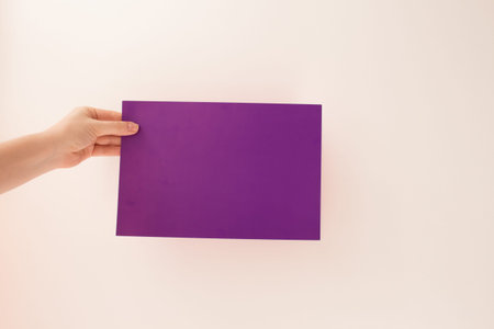 Hands young woman holding blank purle sheet of paper for text and design, mock up on light...