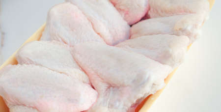 Chilled chicken wings in a yellow tray, fresh meat from the store on a white table. High protein in chickenの写真素材