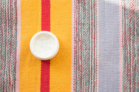 Glass jar of beauty cream on multi-colored background. Concept of skincare cosmetic, spa and...